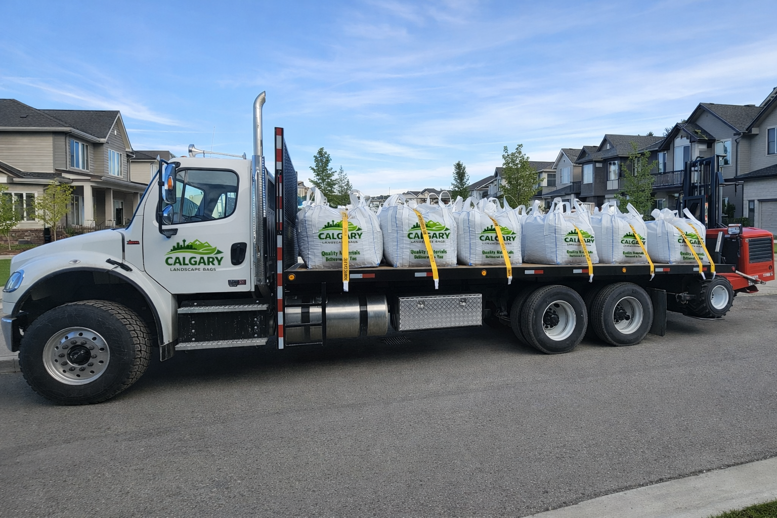 Calgary Landscape Bags delivery truck carrying bulk landscape material bags parked on a residential street with modern homes in the background