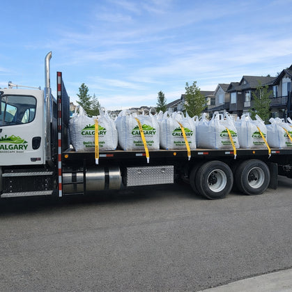 Calgary landscape supply delivery truck transporting bulk bags of rock, sand, and gravel to a residential home in Calgary Alberta